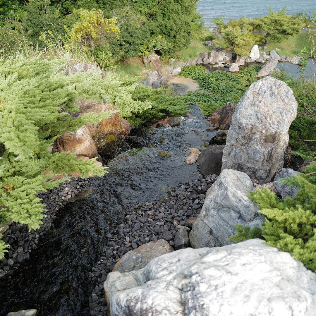 日本庭園の先に広がる鳥羽の静かな入り江に続く小川