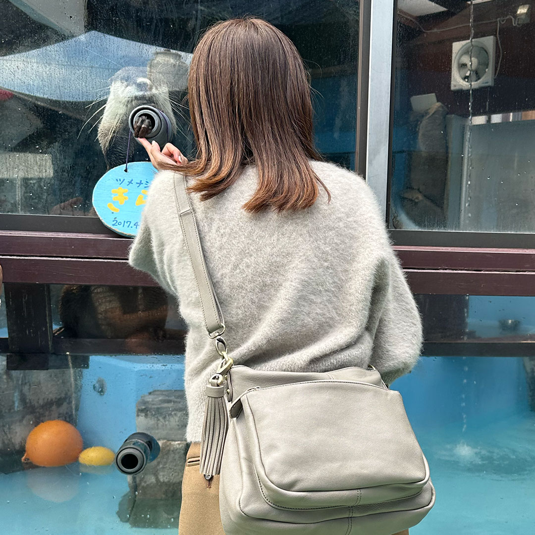 伊勢シーパラダイスでカワウソと握手する女性と旅行ショルダーバッグ