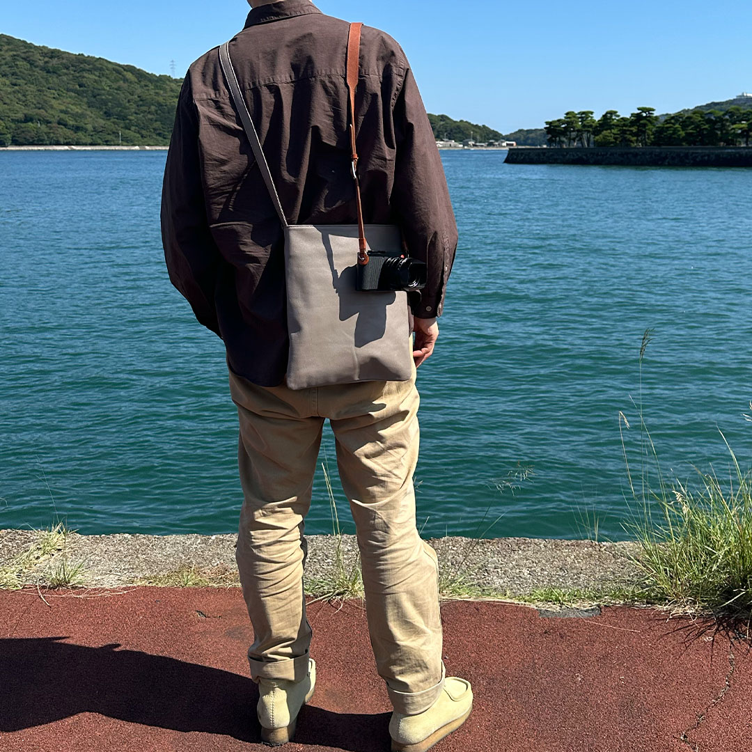 鳥羽湾を望む夫婦旅行の50代男性と旅行バッグと一眼カメラ