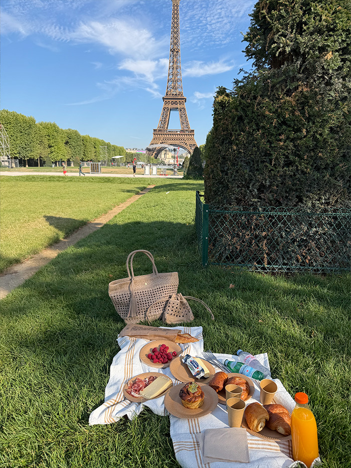 エッフェル塔を背景に芝生でピクニックを楽しむ50代女性のパリ旅行