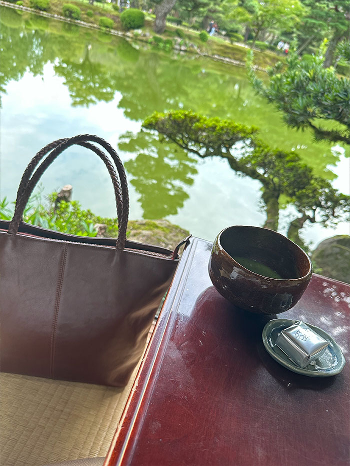 兼六園のお茶屋で過ごす50代女性と本革の旅行バッグ