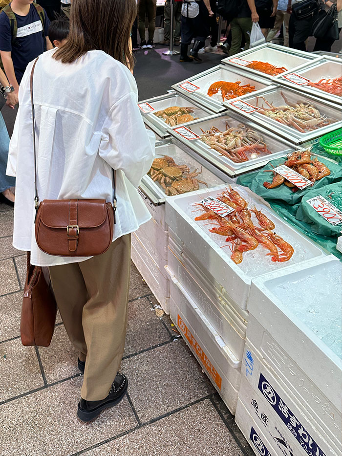 近江町市場で魚介を見ながら歩く50代女性