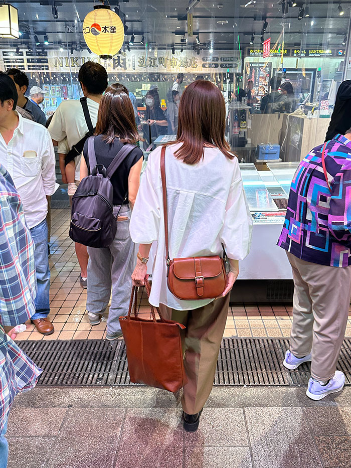 ひがし茶屋街を歩く50代女性と本革の旅行バッグ