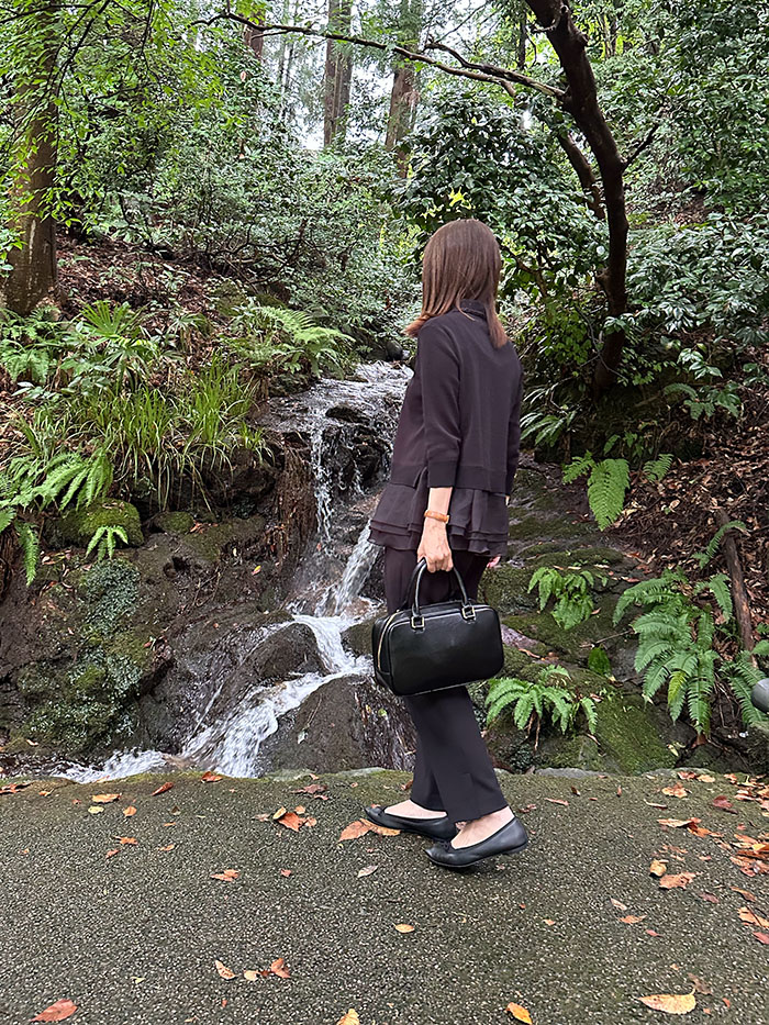 白山比咩神社の滝を眺める50代女性とシモーヌ・ゼン