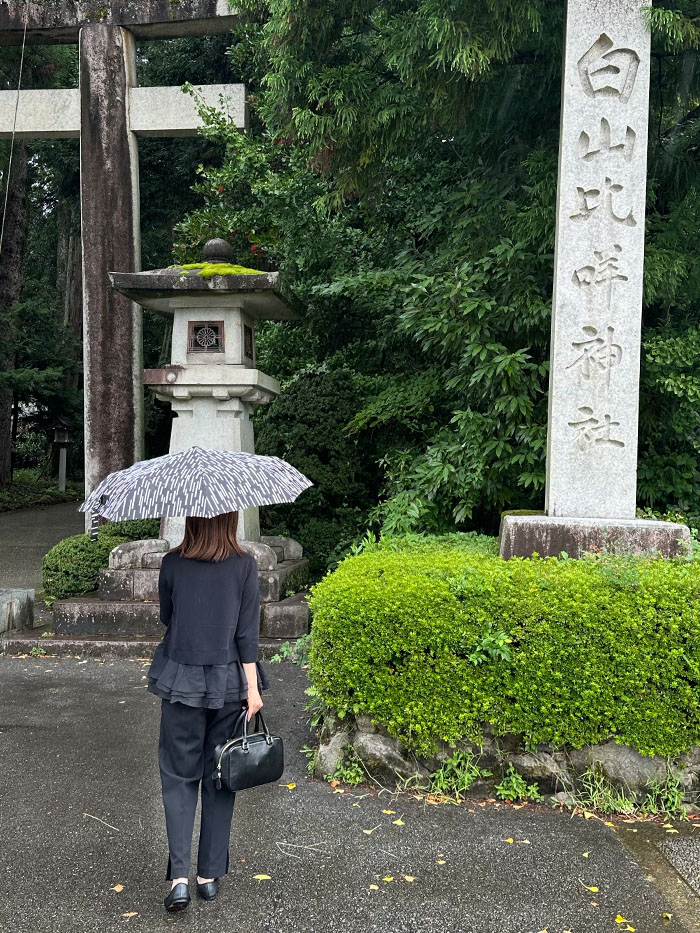 雨の日に白山比咩神社を訪れる50代女性と本革バッグ