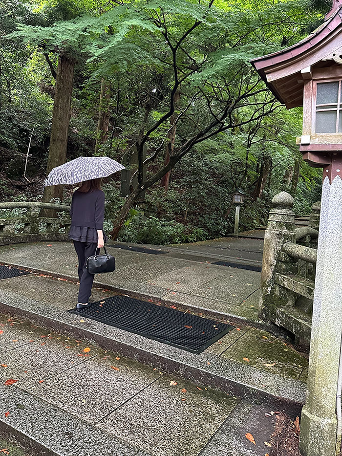 雨に濡れた白山比咩神社の参道を歩く50代女性