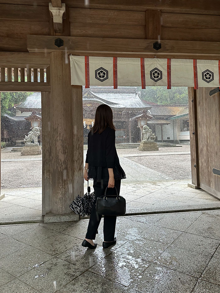 雨宿りをしながら白山比咩神社の境内を眺める50代女性