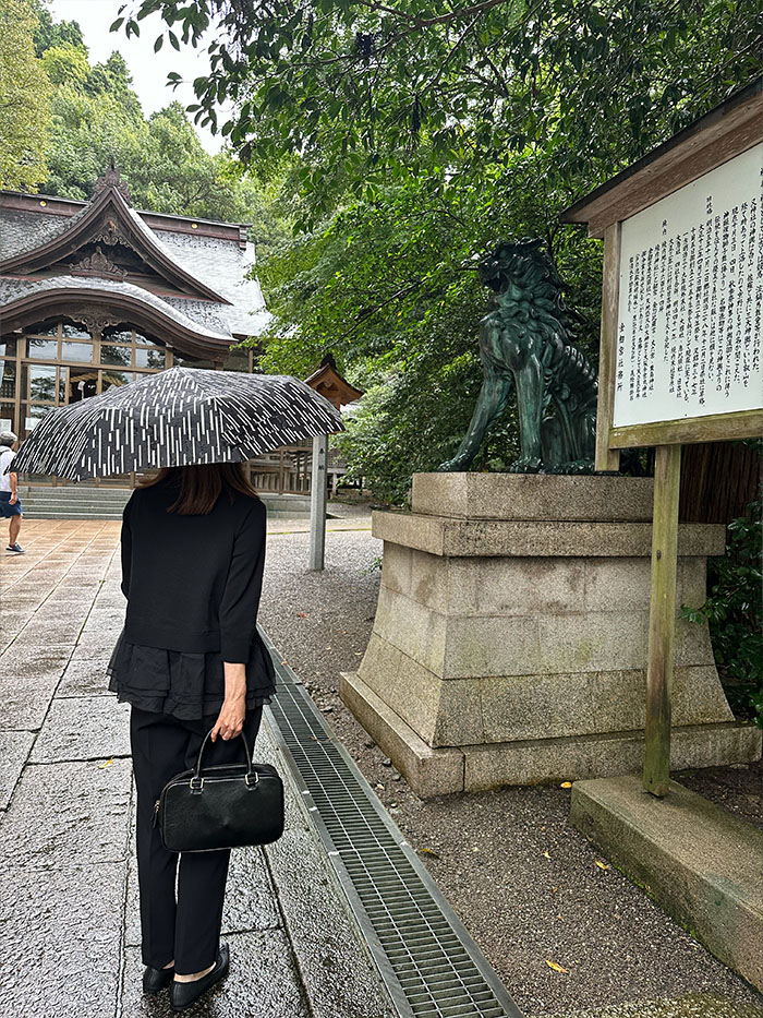 金劔宮を参拝する50代女性とシモーヌ・ゼンの本革バッグ